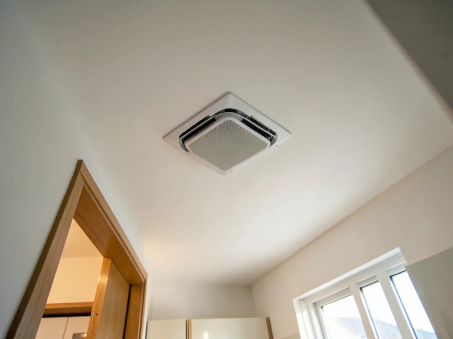 Four-way directional ceiling cassette installed flush with white ceiling in contemporary open-concept kitchen